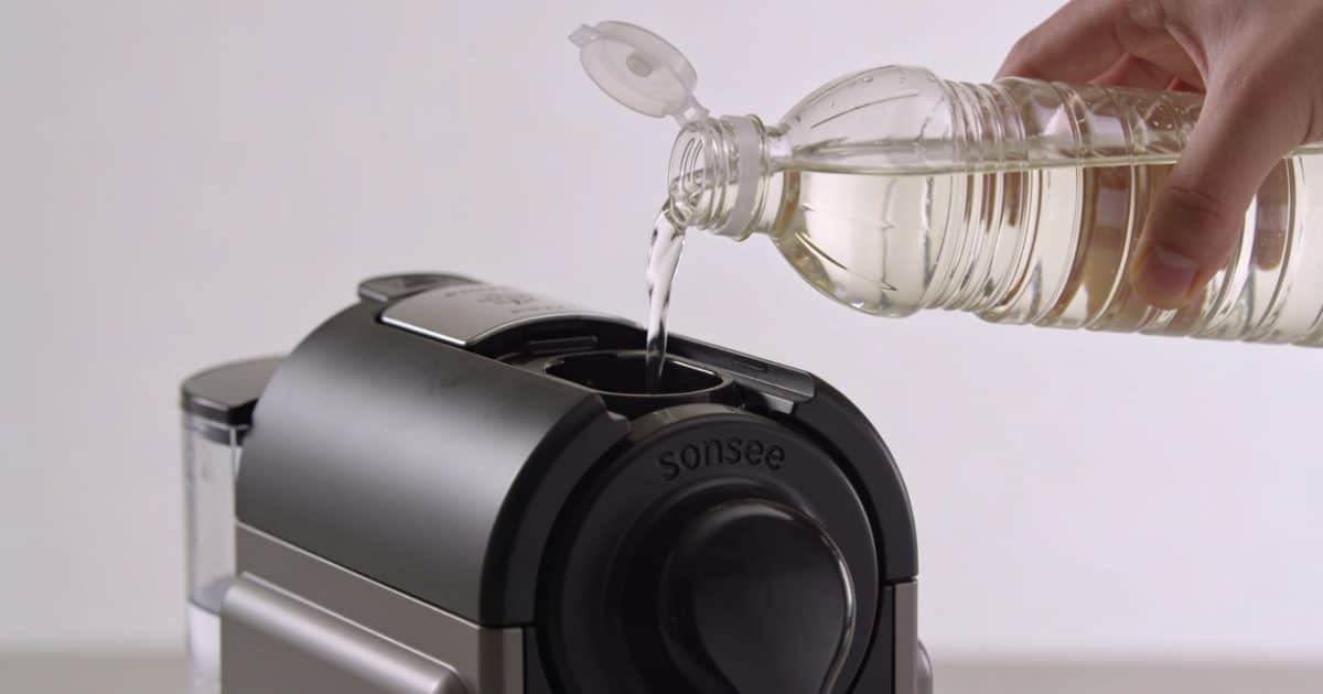 Mains versant du vinaigre blanc dans cafetière Senseo