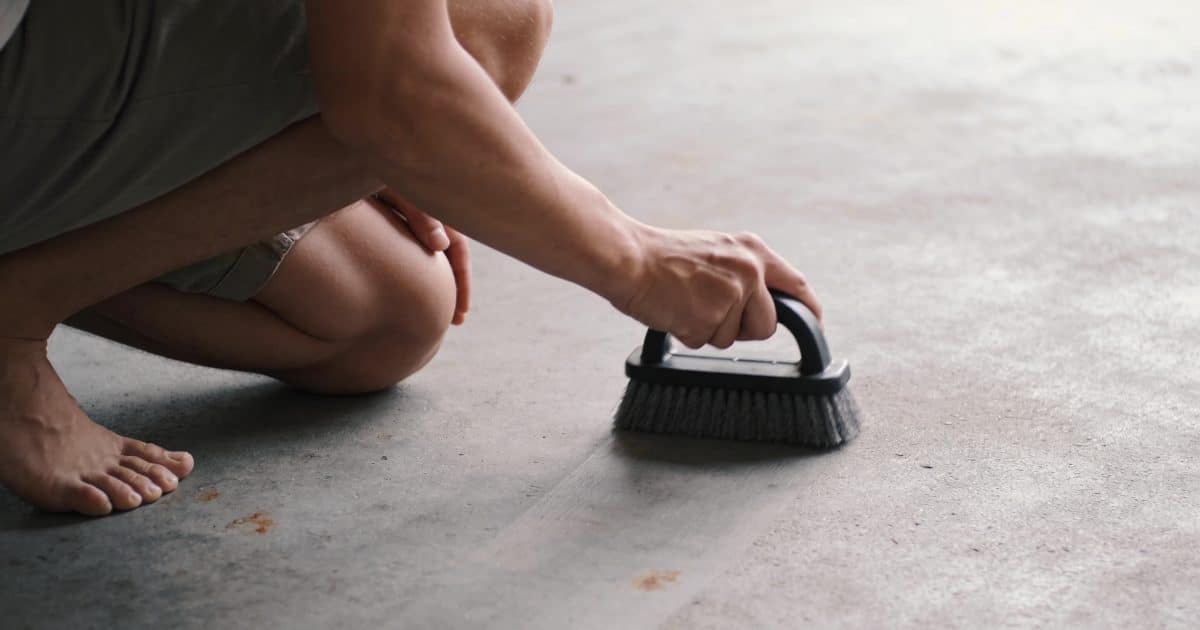 Personne en position accroupie poncant surface beton grise