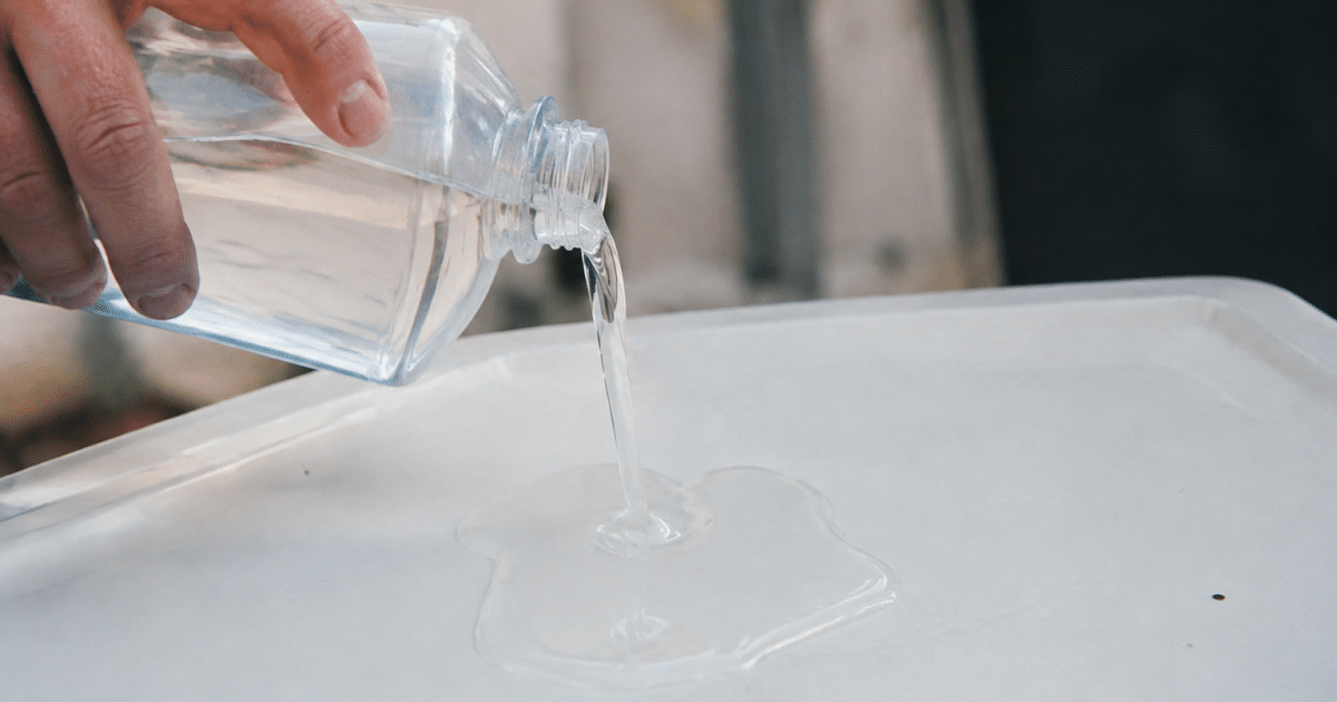 Bouteille de solvant versant liquide sur surface plastique blanche