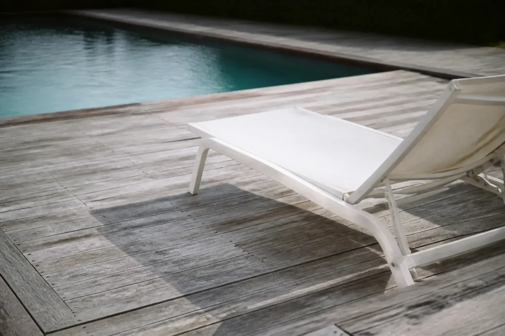 Dalles de bois gris autour d'une piscine, transat blanc
