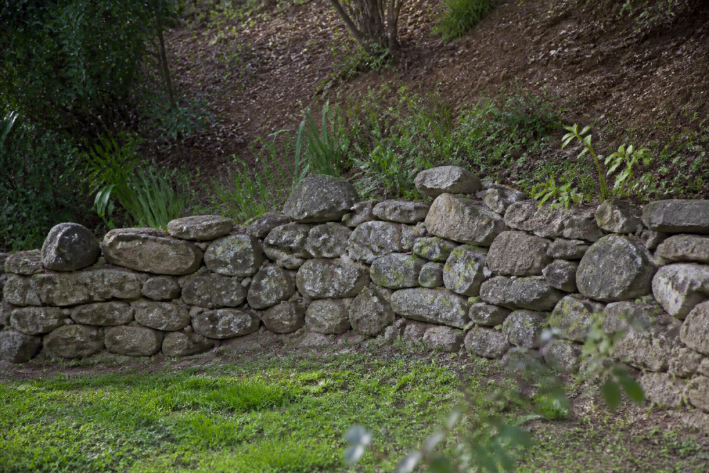 Muret de jardin en pierres avec terre en pente